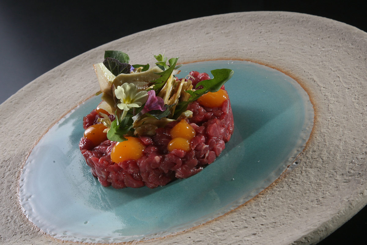 Tartare di agnello con insalatina di carciofi, erbe, fiori di campo e tuorlo d&rsquo;uovo marinato Tartare di agnello con carciofi e uovo marinato